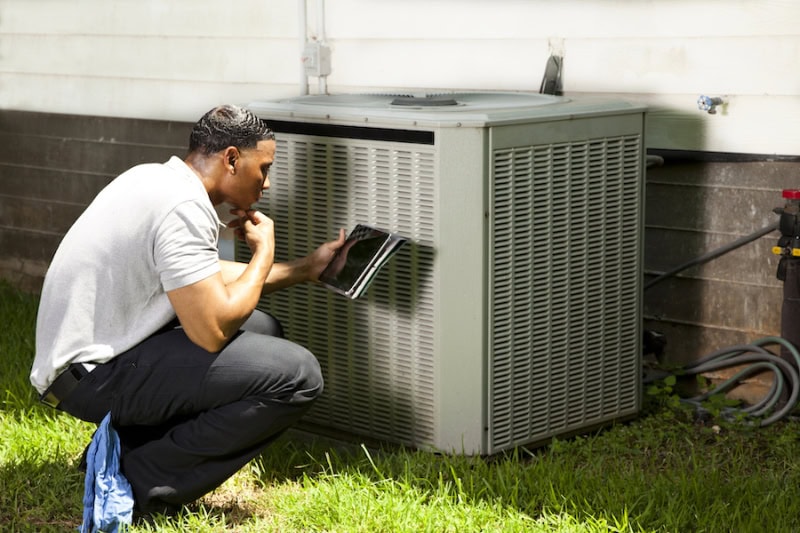 3 Tips to Prevent an AC Breakdown During a Heat Wave. Tech at AC unit.