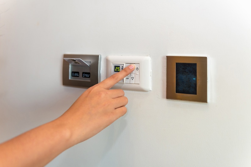 person changing the temperature on a thermostat