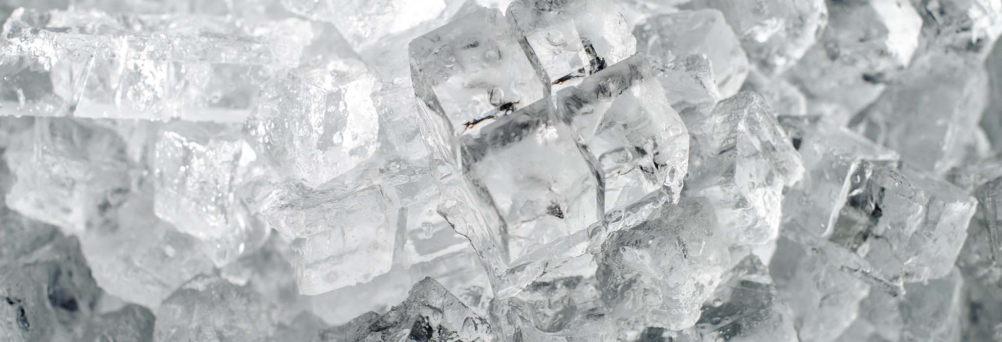 Textured background of a small clear ice cubes in the heap on the ice production plant